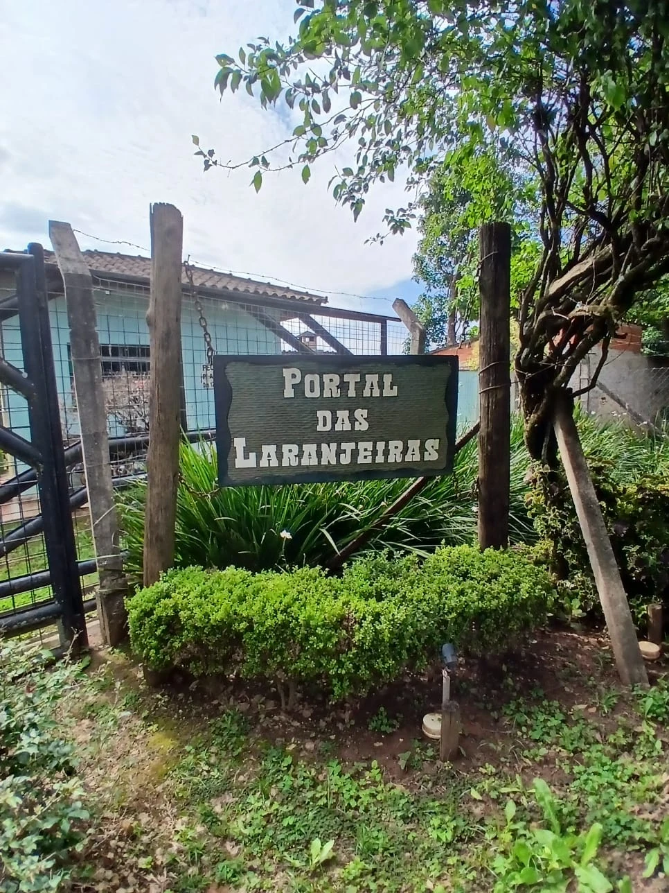 Placa do Portal das Laranjeiras cercada de árvores e jardim
